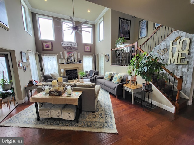 living room with baseboards, ceiling fan, hardwood / wood-style floors, stairs, and a fireplace