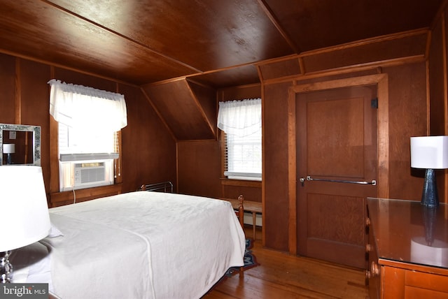 bedroom featuring baseboard heating, cooling unit, wooden walls, and wood finished floors