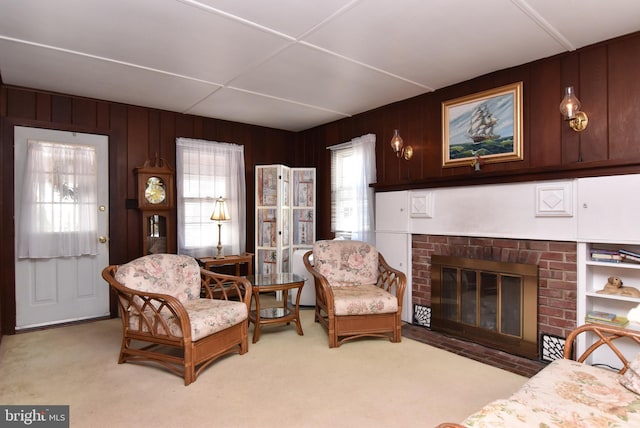 carpeted living room featuring a healthy amount of sunlight, wood walls, and a brick fireplace