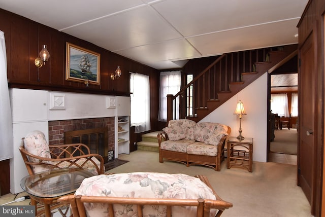 living room with stairway, light colored carpet, and a fireplace