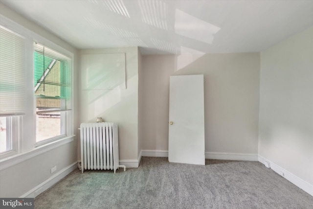 carpeted spare room featuring radiator heating unit