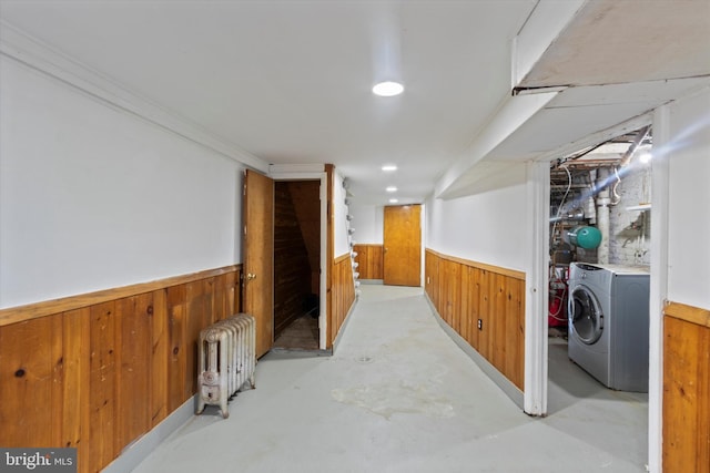 basement with washing machine and clothes dryer, wood walls, and radiator