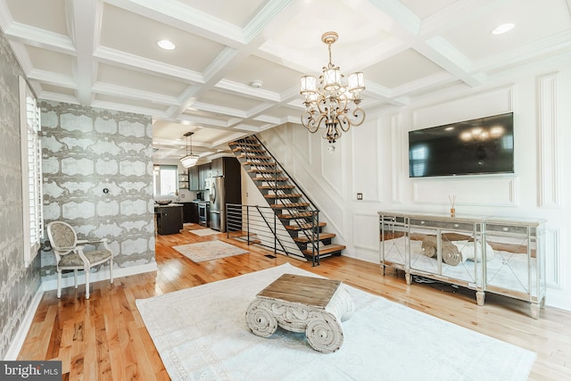 living room with light wood-type flooring, crown molding, coffered ceiling, and a chandelier