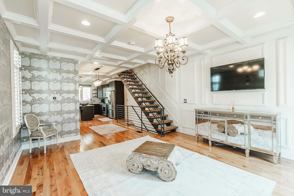 living area with beamed ceiling, coffered ceiling, light wood-style flooring, and stairs