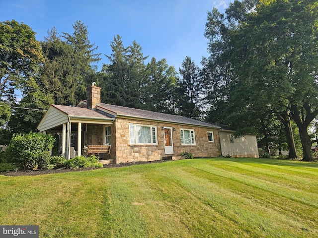 ranch-style home featuring stone siding, a front lawn, and a chimney