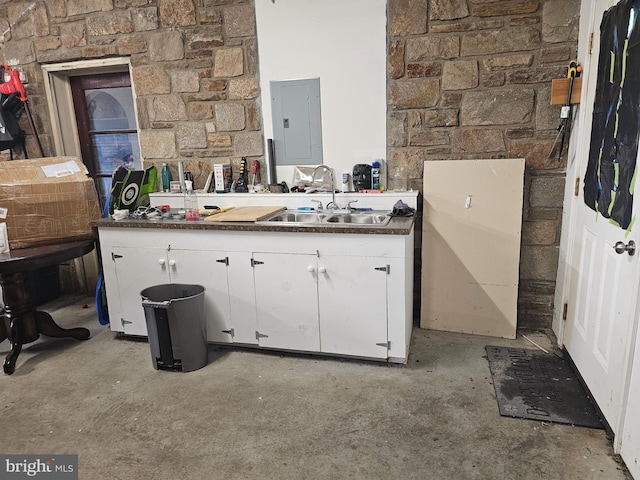 interior space with unfinished concrete flooring, dark countertops, white cabinetry, a sink, and electric panel