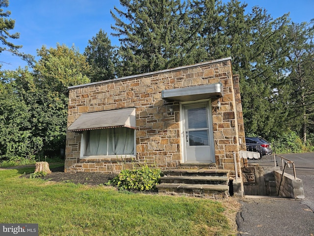 view of front facade with entry steps, stone siding, and a front yard