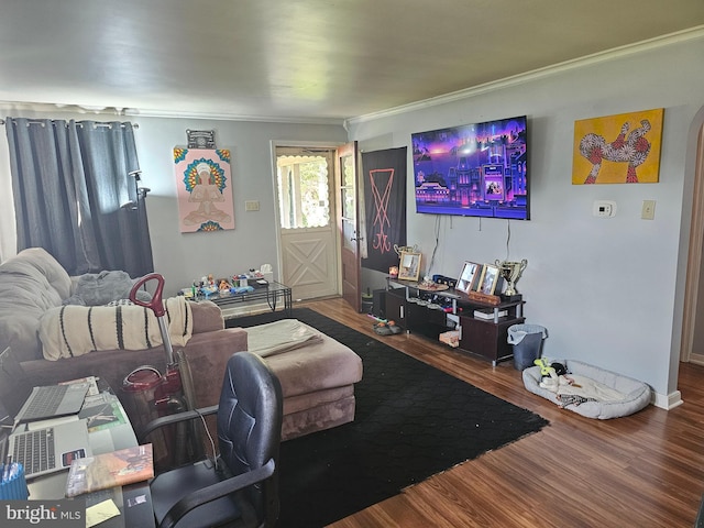 living area featuring arched walkways, ornamental molding, and wood finished floors