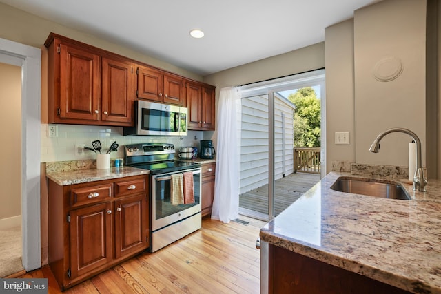 kitchen with light hardwood / wood-style floors, stainless steel appliances, sink, and light stone countertops