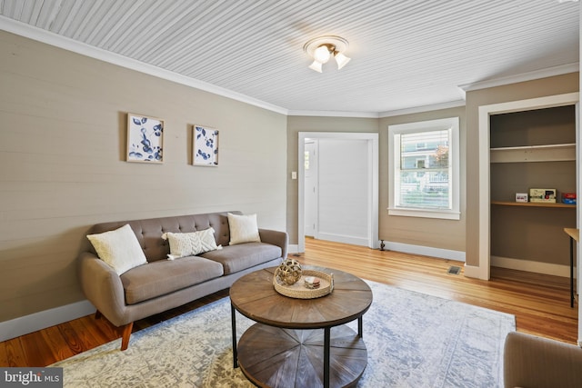 living room with light hardwood / wood-style flooring, built in features, and crown molding