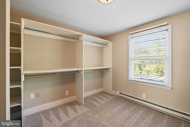 walk in closet with light colored carpet and a baseboard heating unit