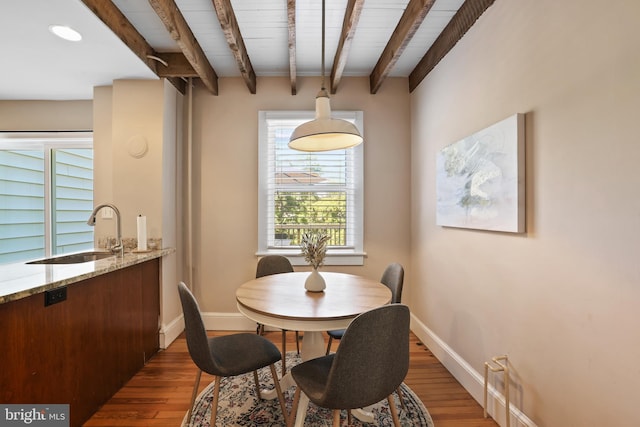 dining area with beam ceiling, dark hardwood / wood-style floors, and sink