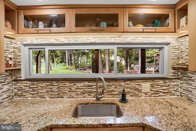 kitchen with sink, light stone countertops, and decorative backsplash