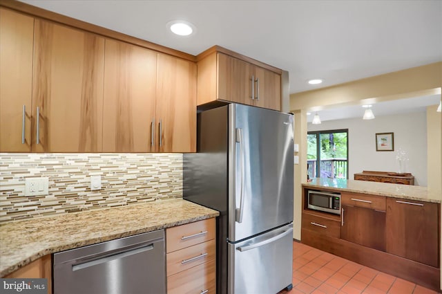 kitchen with backsplash, light stone counters, and stainless steel appliances