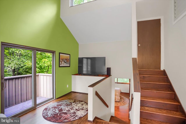 stairway featuring hardwood / wood-style floors and high vaulted ceiling