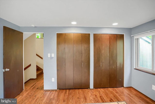 unfurnished bedroom featuring light hardwood / wood-style flooring and multiple closets