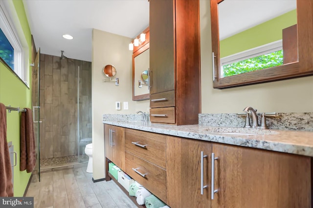 bathroom with a shower with shower door, wood-type flooring, toilet, and vanity