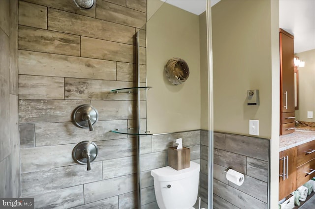 bathroom featuring vanity, toilet, and tile walls