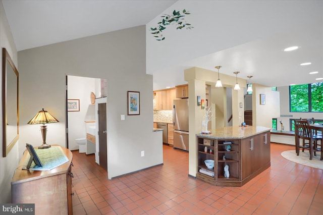 kitchen featuring hanging light fixtures, a center island, vaulted ceiling, stainless steel refrigerator, and decorative backsplash