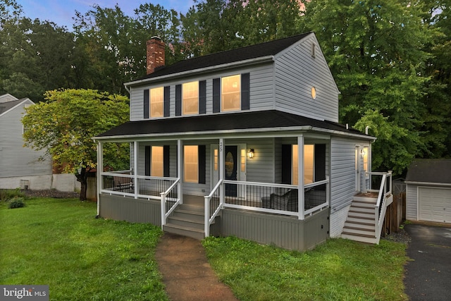 view of front of house featuring covered porch, a garage, a front lawn, and an outdoor structure