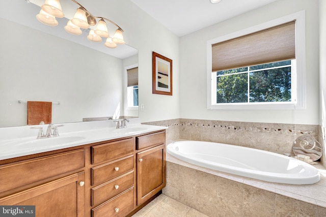 bathroom with tiled tub, vanity, and tile patterned floors