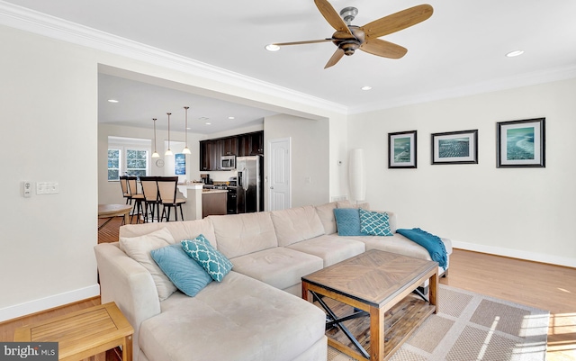 living room with ceiling fan, crown molding, and light hardwood / wood-style floors