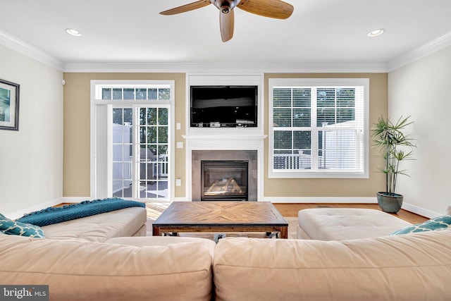 living room featuring ceiling fan, wood-type flooring, crown molding, and plenty of natural light