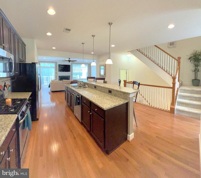 kitchen with dark brown cabinets, a breakfast bar area, an island with sink, and stainless steel appliances