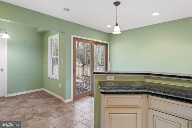 kitchen featuring dark stone countertops, cream cabinets, and decorative light fixtures