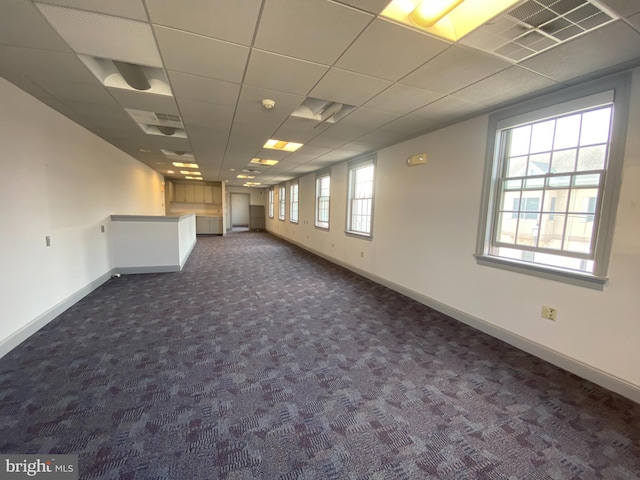 empty room featuring visible vents, baseboards, dark colored carpet, and a drop ceiling