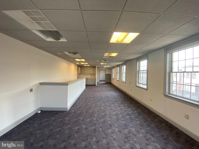 unfurnished room with a drop ceiling, baseboards, visible vents, and dark carpet