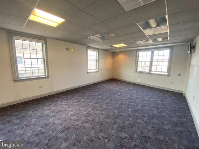 carpeted spare room with visible vents, baseboards, and a drop ceiling