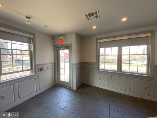 doorway to outside featuring visible vents, recessed lighting, a decorative wall, and a wainscoted wall