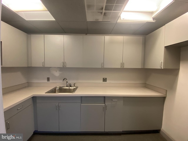 kitchen with a sink, white cabinetry, gray cabinets, and light countertops