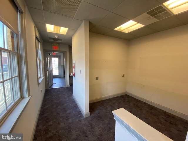 hall with baseboards, a paneled ceiling, visible vents, and dark carpet