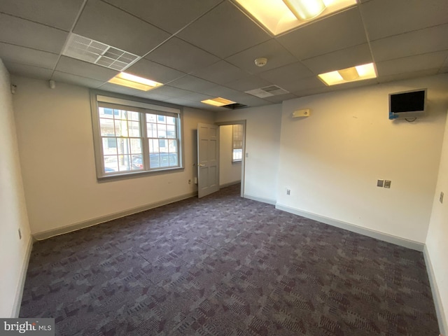 carpeted empty room featuring a paneled ceiling and baseboards