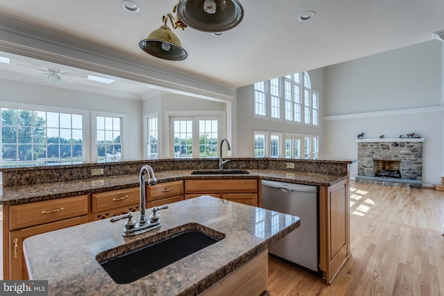 kitchen featuring light wood-type flooring, dark stone counters, dishwasher, sink, and ceiling fan