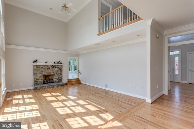 unfurnished living room featuring high vaulted ceiling, a wealth of natural light, ceiling fan, and a stone fireplace