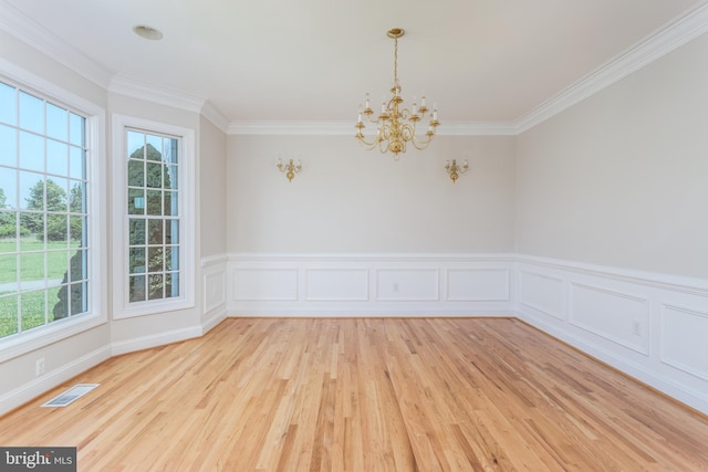 empty room featuring crown molding, a healthy amount of sunlight, hardwood / wood-style floors, and a chandelier