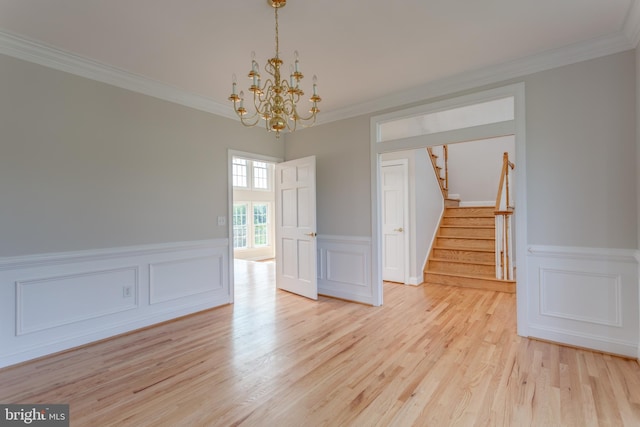 empty room with light hardwood / wood-style floors, a notable chandelier, and ornamental molding