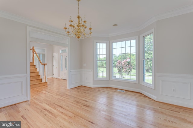 empty room featuring light hardwood / wood-style flooring, ornamental molding, a chandelier, and a healthy amount of sunlight