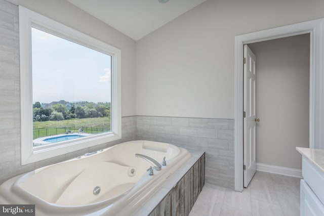 bathroom featuring tile walls, vaulted ceiling, tile patterned floors, and a relaxing tiled tub