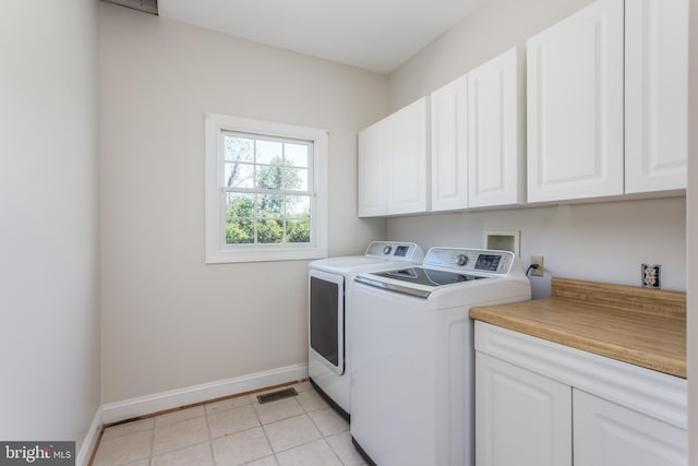 laundry room featuring light tile patterned flooring, cabinets, and washing machine and dryer