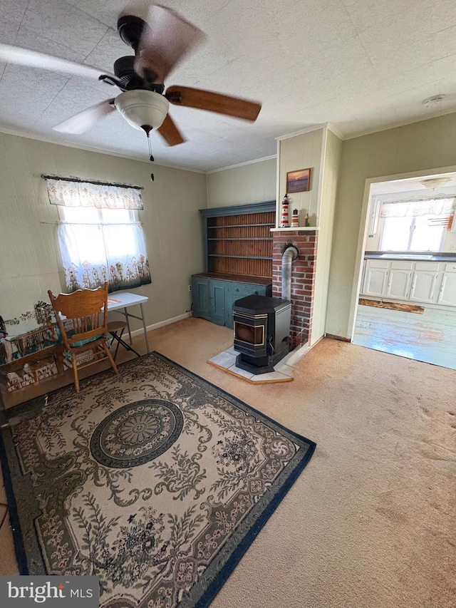 living room featuring a textured ceiling, carpet, a wood stove, and crown molding