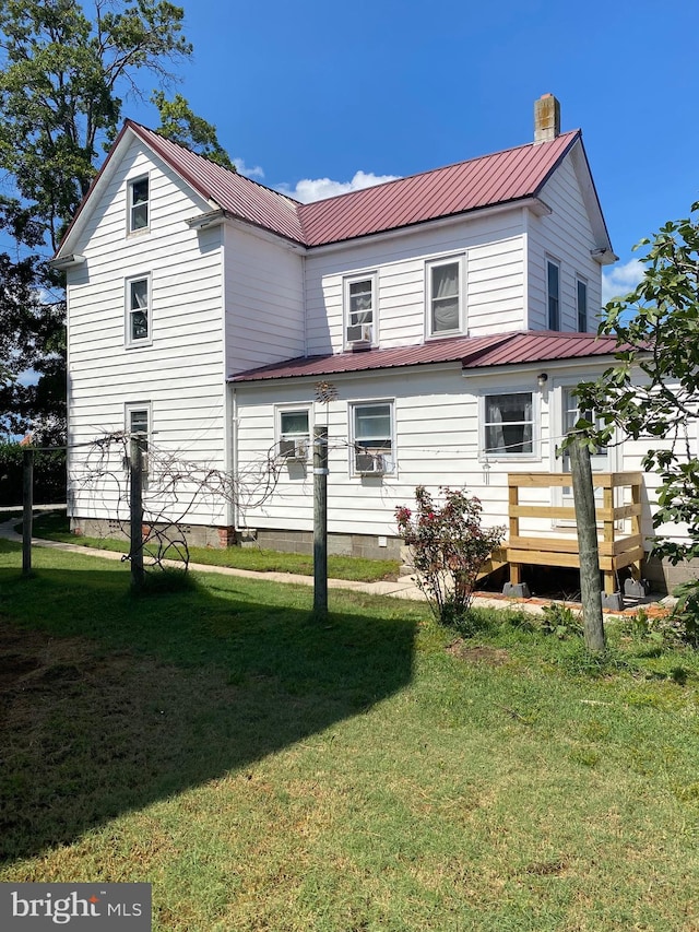 rear view of house with metal roof, a yard, a deck, and a chimney