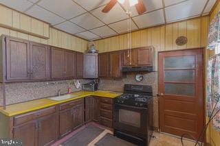 kitchen with black gas stove, a paneled ceiling, ceiling fan, and sink