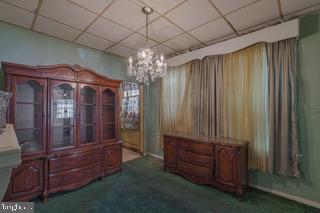 misc room featuring a paneled ceiling, an inviting chandelier, and carpet