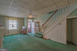 interior space featuring ceiling fan, carpet floors, and a drop ceiling