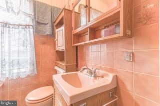 bathroom featuring vanity, toilet, and tile walls