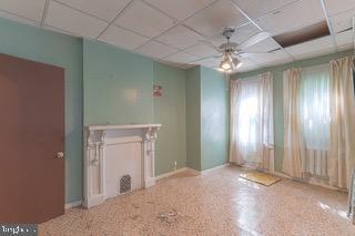 empty room with ceiling fan and a drop ceiling